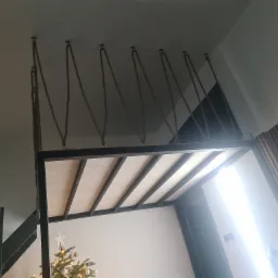 Wnętrze pokoju z antresolą podwieszoną na linach, widoczna choinka w rogu pomieszczenia.