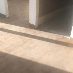 Jasne panele podłogowe ułożone w nowym pomieszczeniu, widoczne promienie słoneczne, ściany w trakcie wykończenia.