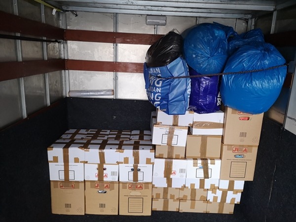 Wnętrze furgonetki wypełnione kartonami zabezpieczonymi taśmą i workami na śmieci, gotowymi do transportu, widoczne brązowe listwy zabezpieczające na ścianach.