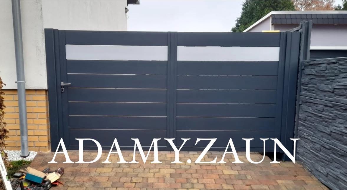 Nowoczesna, dwuskrzydłowa brama wjazdowa w kolorze grafitowym z poziomymi panelami i dwoma pasami prześwitującymi, zamontowana na posesji z kostką brukową i elementami wykończenia z kamienia...