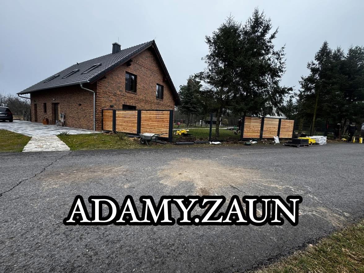 Nowoczesne ogrodzenie z drewnianymi panelami horyzontalnymi, otaczające posesję z ceglanym domem. Widoczne narzędzia i materiały budowlane.
