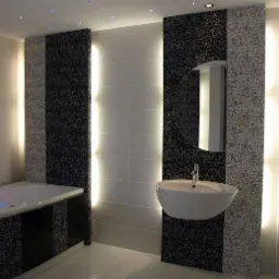 Wykończona łazienka z białą umywalką nablatową, okrągłym lustrem i panelami ściennymi w czarno-białe kwiaty, podświetlona listwami LED i punktowym oświetleniem sufitowym.