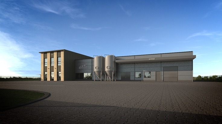 Nowoczesny budynek przemysłowy z dwoma srebrnymi silosami na zewnątrz, widok z poziomu gruntu, błękitne niebo w tle.