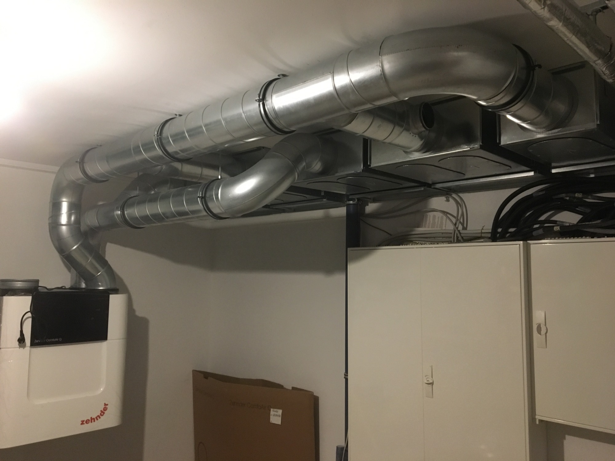 System wentylacji mechanicznej z rekuperacją Zehnder ComfoAir Q, z widocznymi kanałami wentylacyjnymi w pomieszczeniu technicznym.