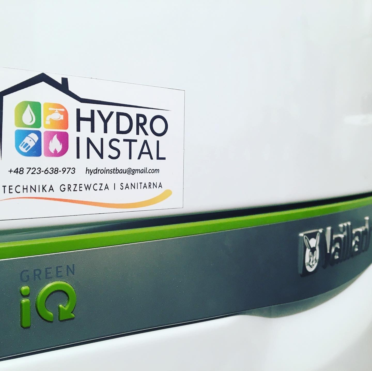 Naklejka firmy Hydro Instal z numerem telefonu i adresem e-mail na tle urządzenia Vaillant Green iQ.