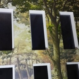 Der-bud - Ściana z fototapetą leśną i wkomponowanymi oknami z białymi ramami. Nietypowe połączenie natury i architektury wewnątrz pomieszczenia.