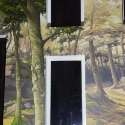 Der-bud - Dwa pionowe, prostokątne lustra z białą ramą na ścianie z fototapetą przedstawiającą las. Na tapecie widoczne drzewa z wyrazistymi twarzami.