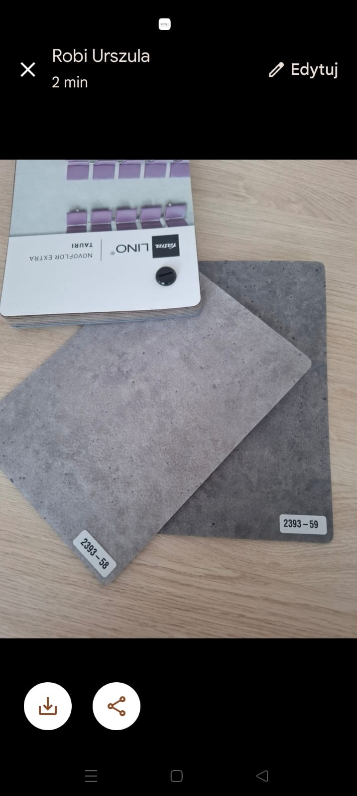 Katalog z próbkami wykładzin Fatra Lino Novoflor Extra Tauri, prezentujący dwa odcienie szarości z numerami 2393-58 i 2393-59 na drewnianym podłożu.