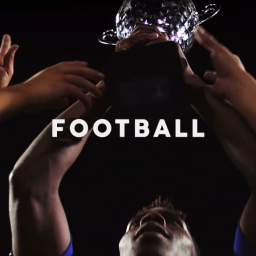 Szydzisz - Ujęcie od dołu: Ręce unoszą błyszczący puchar nad głową, ciemne tło, widoczna twarz osoby w dolnej części kadru.