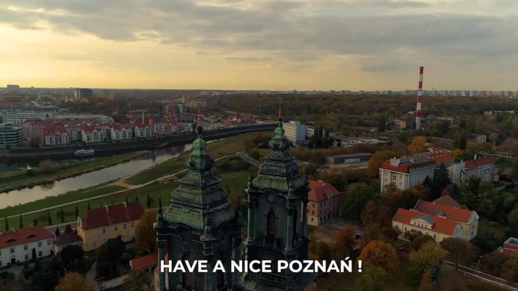 Panoramiczny widok na Poznań z perspektywy drona, ukazujący katedrę, rzekę Wartę, budynki mieszkalne i przemysłowe w jesiennej scenerii.