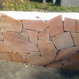 Usługi budowlano remontowe Marcin Wojcieszek - Mur z nieregularnych, płaskich kamieni w odcieniach brązu i beżu, tworzących dekoracyjną ścianę na zewnątrz.