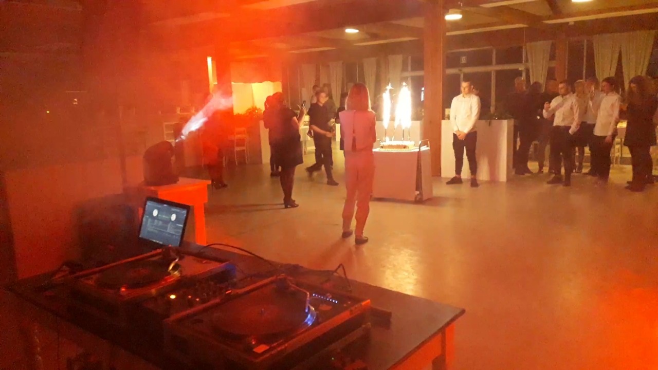 DJ miksuje muzykę w Łodzi podczas imprezy z efektami specjalnymi i tortem z fontannami.