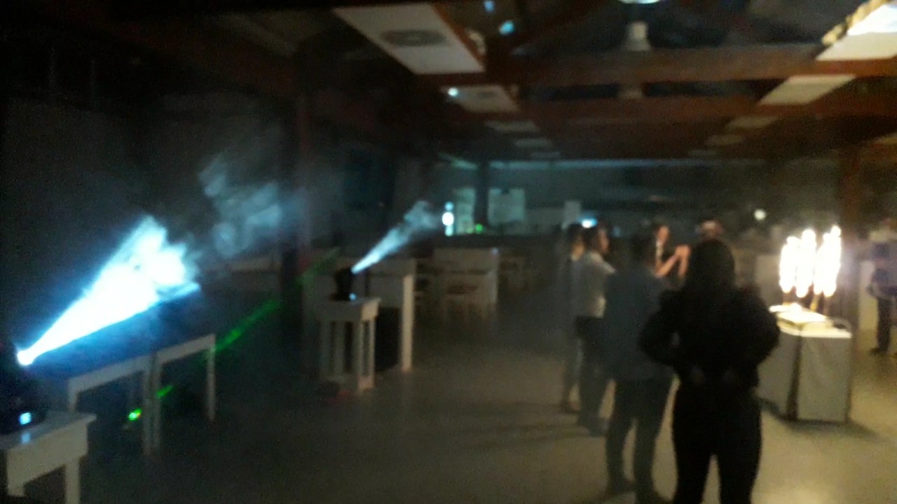 Sala bankietowa z oświetleniem scenicznym, reflektory rzucają snopy światła, w tle widoczni goście.