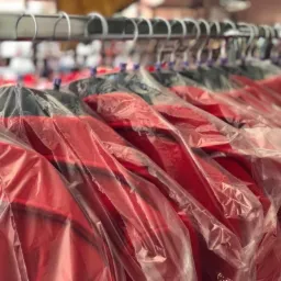 Rząd czerwonych kanap w przezroczystych pokrowcach ochronnych, wiszących na metalowym wieszaku.