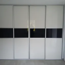 Czterodrzwiowa szafa przesuwna z białymi panelami i poziomym pasem z czarnego szkła, widoczna na tle jasnej podłogi i ściany.