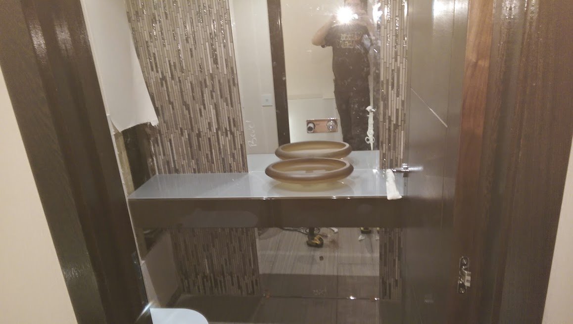 Łazienka w trakcie wykańczania: dwie owalne umywalki na blacie, mozaika na ścianie, widoczne niedociągnięcia w wykończeniu.