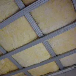 Sufit podwieszany: metalowa konstrukcja z wypełnieniem z wełny mineralnej, widok od dołu, etap montażu.