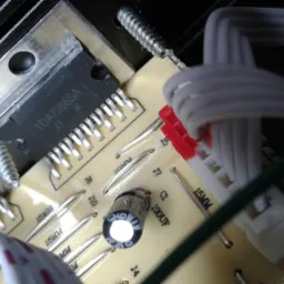 Zbliżenie na płytkę drukowaną z elementami elektronicznymi, w tym układ scalony TDA7266SA, kondensator i złącza kablowe, widoczne ślady lutowania.
