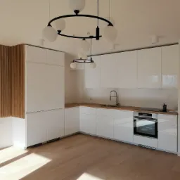 Nowoczesna, minimalistyczna kuchnia z białymi, lakierowanymi szafkami, drewnianym blatem i dekoracyjną ścianą z drewnianych listewek. Okrągła lampa sufitowa z białymi kulami nad wyspą kuchenną.