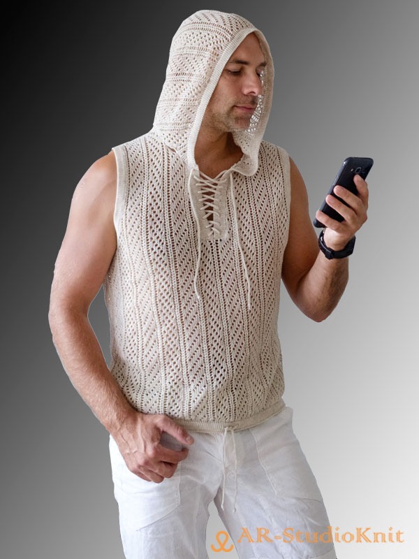 Mężczyzna w beżowej, ażurowej kamizelce z kapturem, wiązanej na dekolcie, przegląda coś na smartfonie.