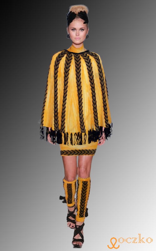 Żółto-czarny, dziergany komplet: poncho z frędzlami, mini spódnica i ocieplacze na nogi, prezentowany na modelce na szarym tle.