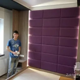 Montaż tapicerowanego panelu ściennego w sypialni w Bytomiu, widoczny pracownik z narzędziami, oświetlenie LED podkreślające strukturę paneli.