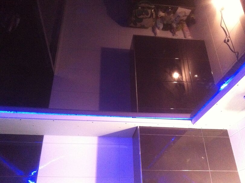 Podwieszany sufit z czarnymi panelami i niebieskim oświetleniem LED, widok z dołu.