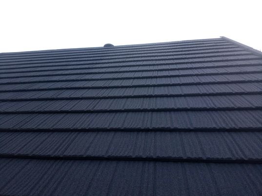 Granatowy dach z blachy trapezowej, widok z dołu pod kątem, regularne ułożenie paneli z widoczną fakturą materiału.