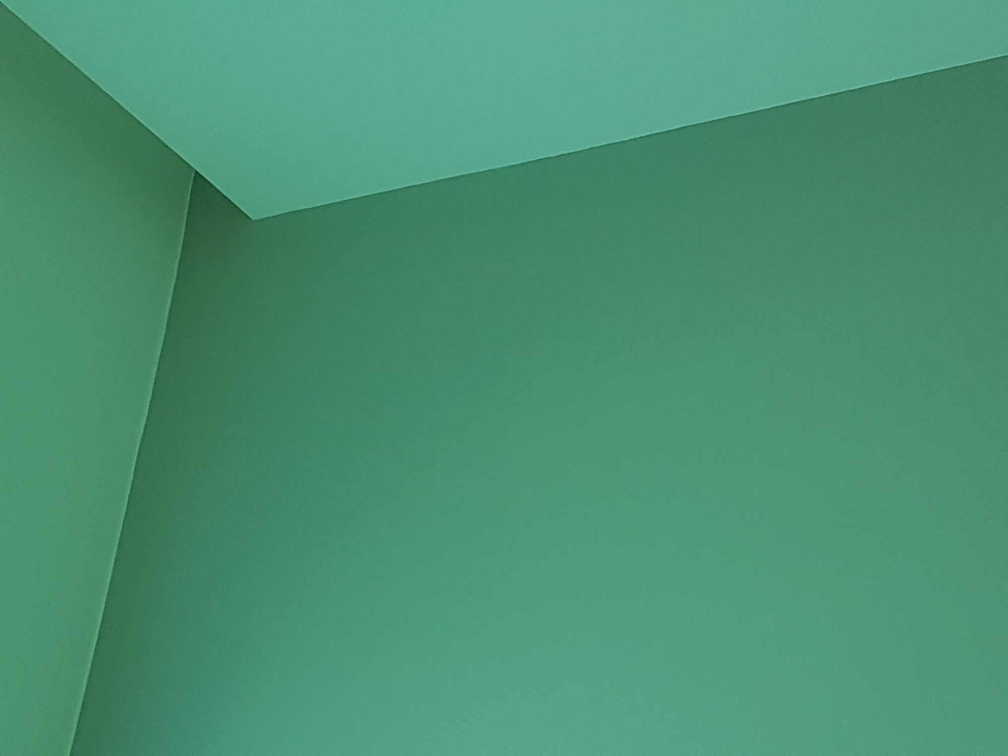 Pomieszczenie po malowaniu ścian i sufitu na jednolity, zielony kolor, widoczny róg pokoju.