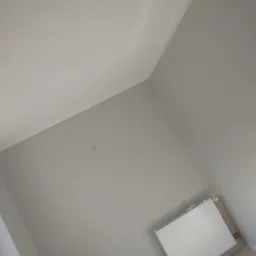 Pomieszczenie po malowaniu ścian na szaro, widoczny biały grzejnik i listwa przysufitowa.