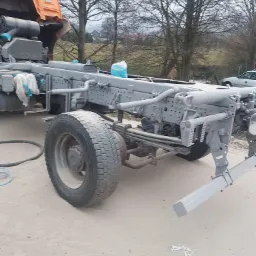 Rama samochodu ciężarowego po oczyszczeniu i zabezpieczeniu, pomalowana na szaro, widoczne elementy podwozia i koło, na ziemi resztki zabezpieczeń.