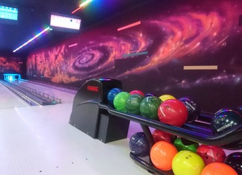 Tor do kręgli z kolorowymi kulami w Stęszewie, oświetlony neonowymi światłami, z galaktycznym motywem na ścianie.