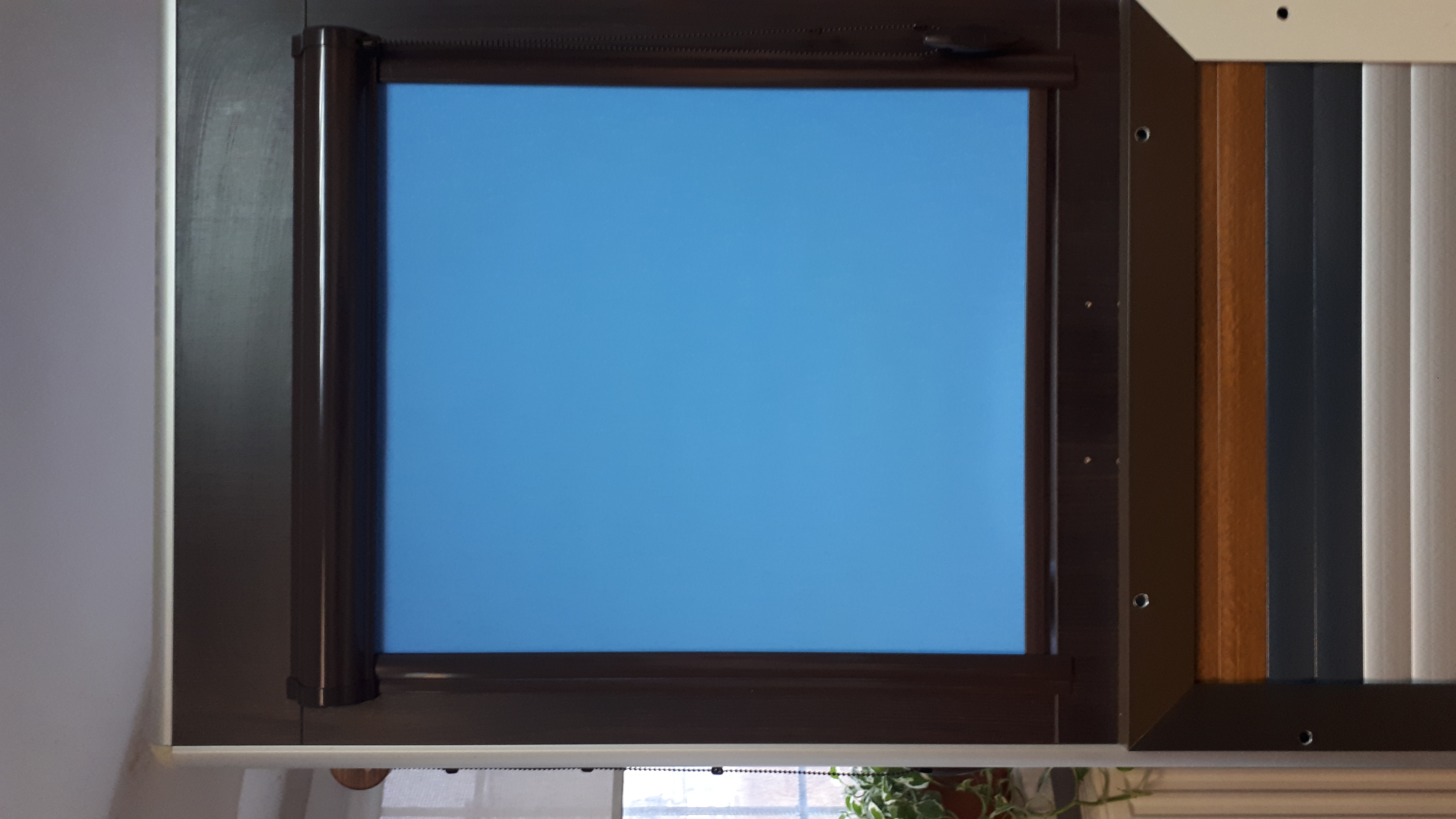 Ekspozycja próbek różnych kolorów i typów osłon okiennych, w tym brązowej kasety z błękitnym materiałem oraz pionowych listewek w odcieniach brązu, szarości i bieli.