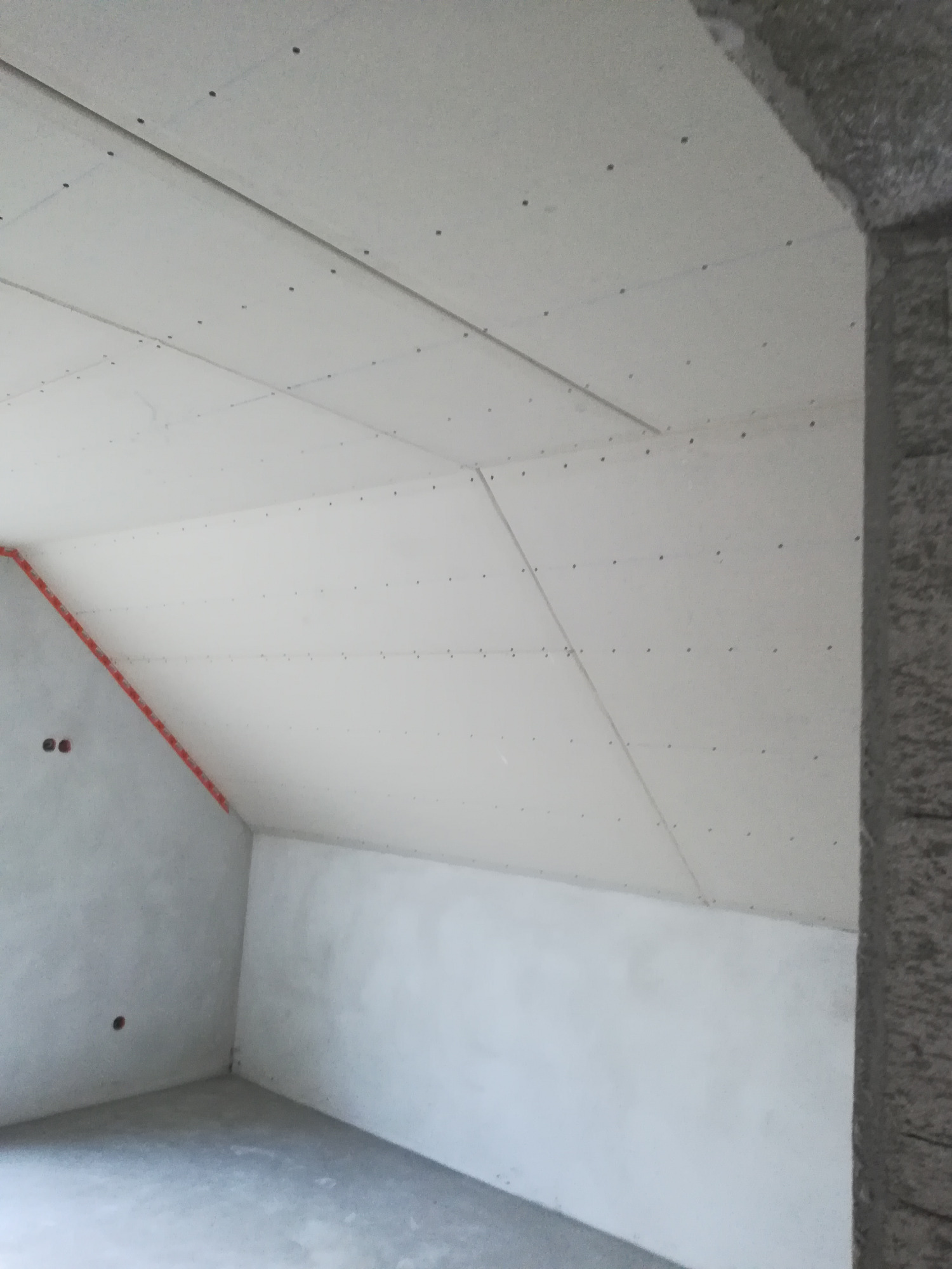 Montaż płyt gipsowo-kartonowych na poddaszu, widoczne profile i wkręty, ściany przygotowane do malowania.