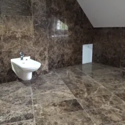 Łazienka wykończona marmurem Emperador Dark, prezentująca bidet i detale wykończenia ścian oraz podłogi z kamienia.