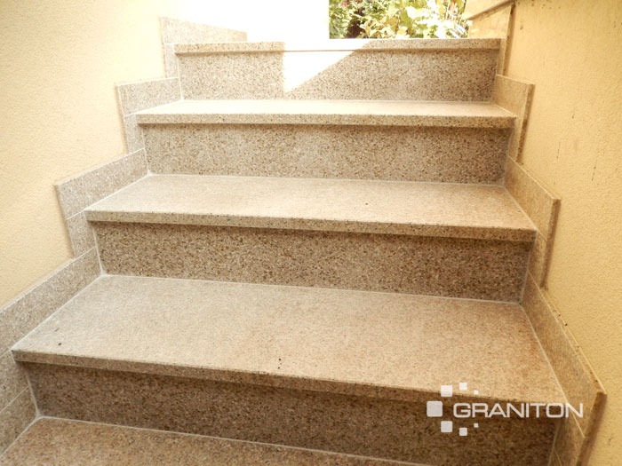 Granitowe schody zewnętrzne Yellow Rock z płomieniowaną powierzchnią antypoślizgową, widok z dołu, logo firmy w prawym dolnym rogu.