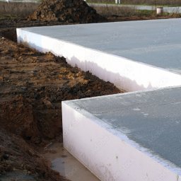 FULER Sp. z o.o. - Przygotowany fundament z izolacją termiczną na budowie w Warszawie, widok z poziomu gruntu na wykopany rów wokół fundamentu.