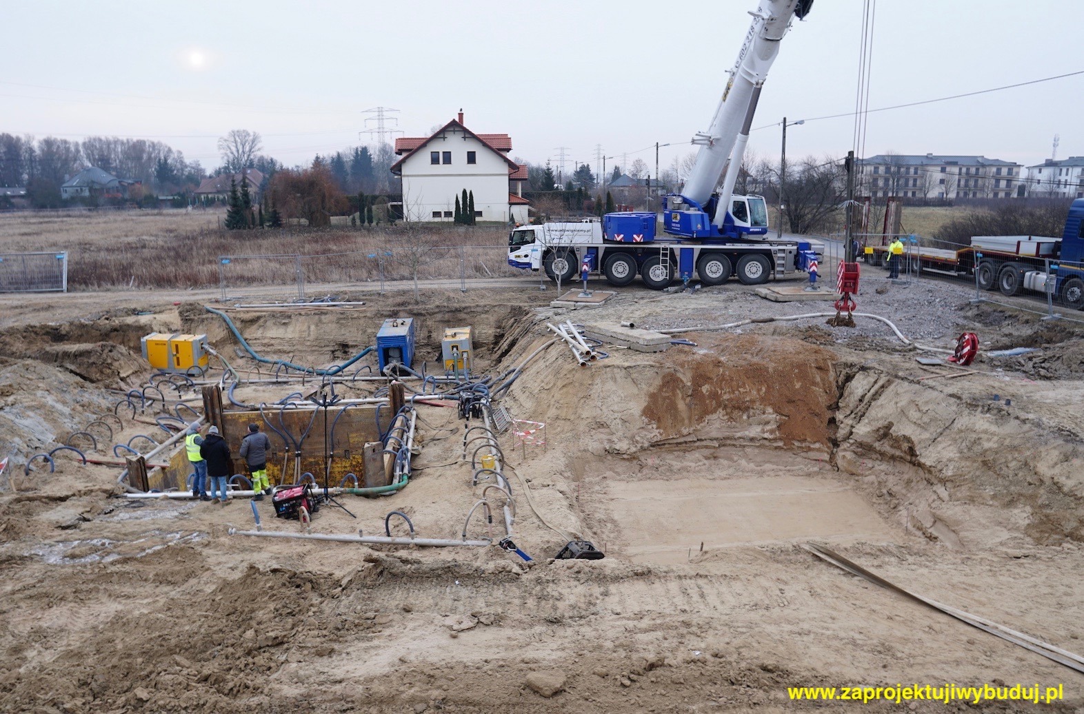 Budowa wykopu zabezpieczonego ściankami berlińskimi z użyciem igłofiltrów, widoczny dźwig i pracownicy w żółtych kamizelkach.