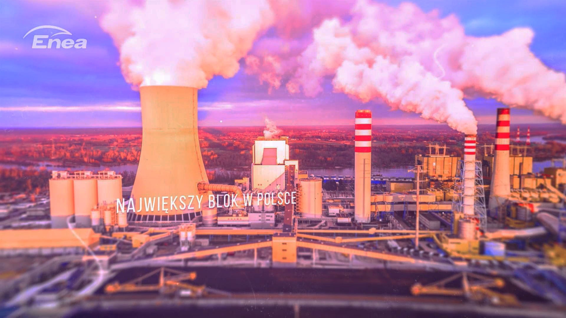 Panoramiczny widok na elektrownię z chłodnią kominową i kominami, z widocznymi smugami dymu w wieczornym oświetleniu.