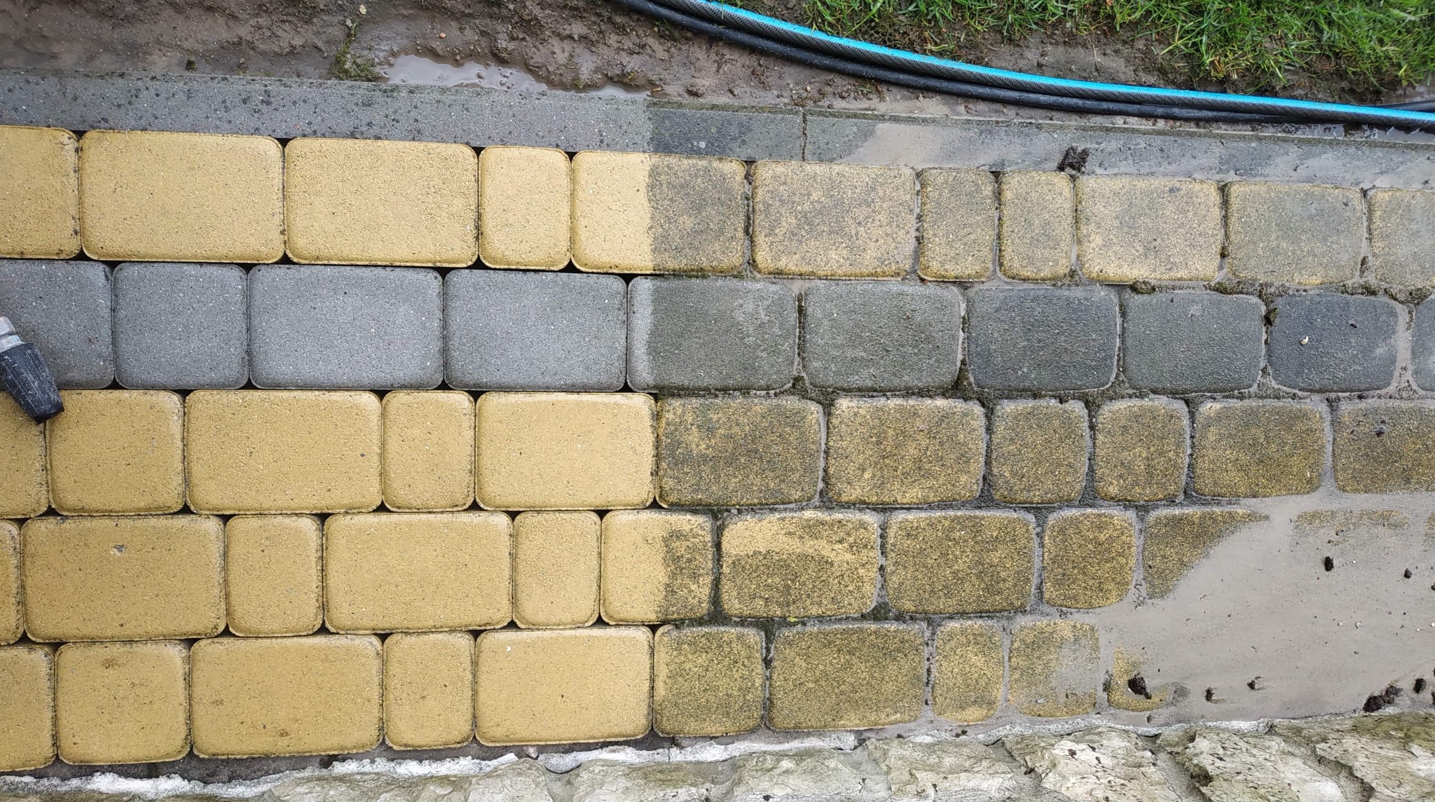 Czyszczenie kostki brukowej: widoczna różnica między umytą a brudną częścią, z użyciem lancy ciśnieniowej i węża ogrodowego.