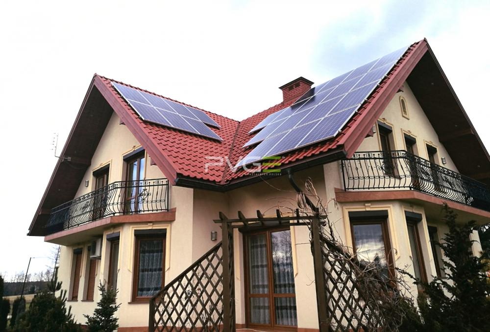 Dwukondygnacyjny dom z czerwonym dachem i panelami fotowoltaicznymi na dachu, widok z dołu.