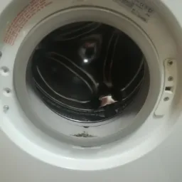 Otwarty bęben pralki z widocznymi śladami zabrudzeń i osadów na dolnej uszczelce.