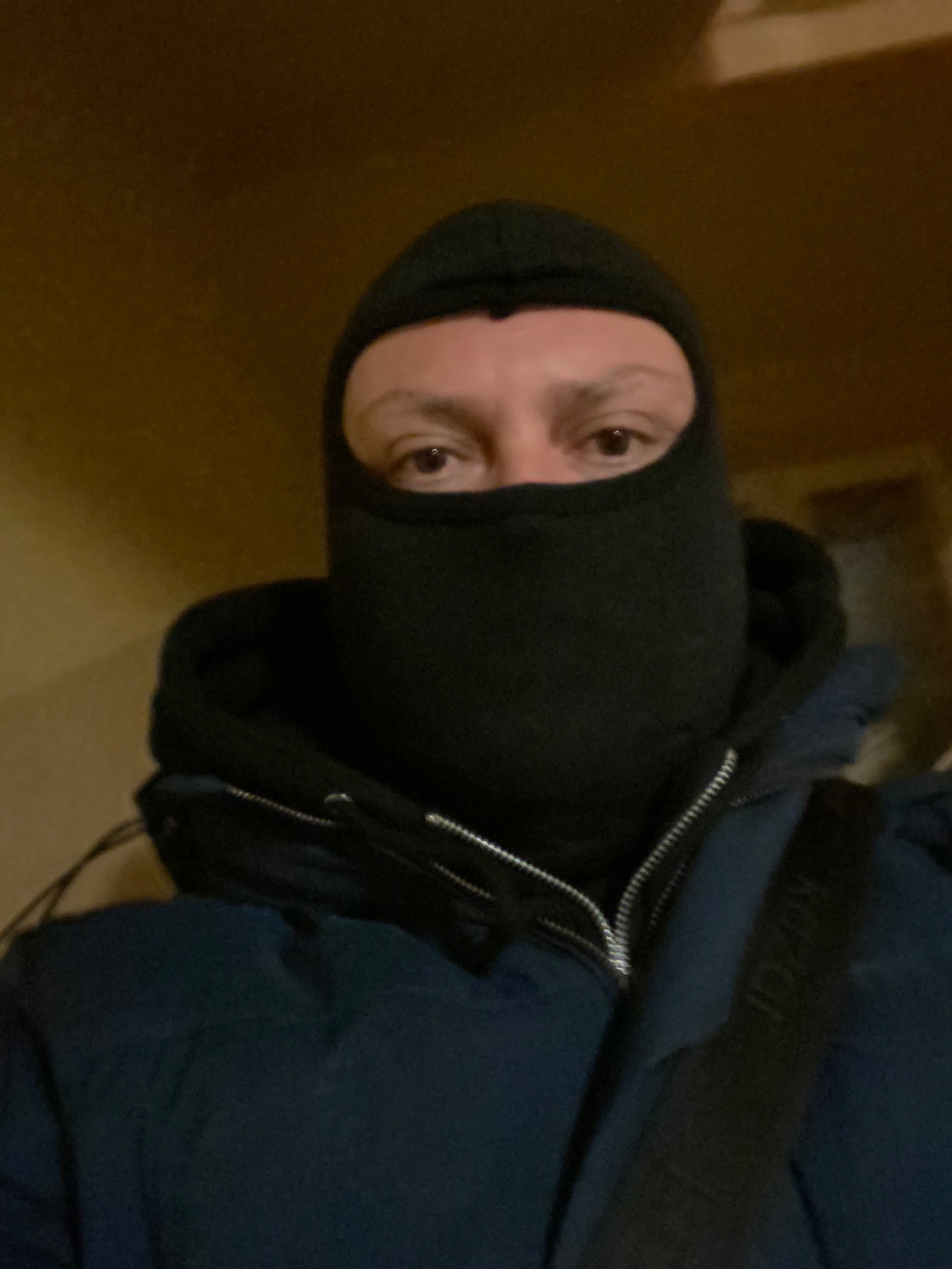 Mężczyzna w czarnej kominiarce, ubrany w ciemną kurtkę, widoczne tylko oczy.