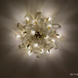 Sufitowa lampa w stylu glamour z licznymi kryształowymi elementami w kształcie liści, oświetlona ciepłym światłem, widziana z dołu.