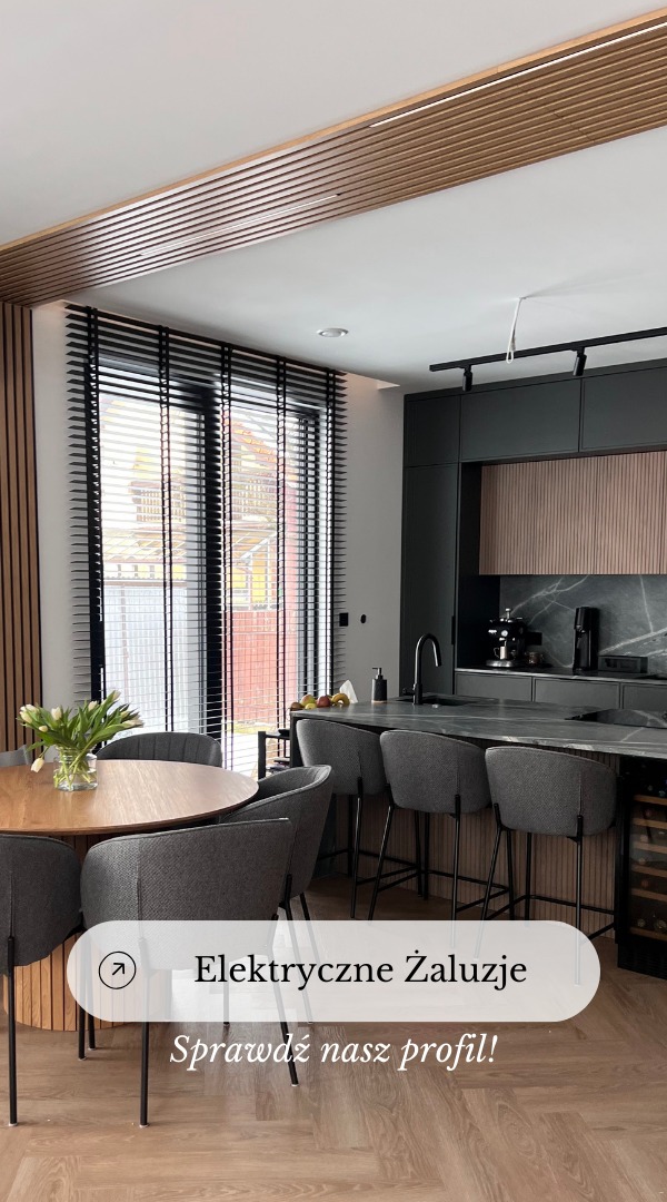 Nowoczesna kuchnia z czarnymi żaluzjami poziomymi w oknie, drewnianym stołem z szarymi krzesłami i wyspą kuchenną z hokerami.