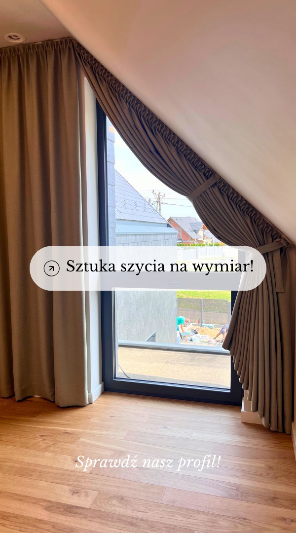 Beżowe, drapowane zasłony na oknie w skośnym dachu w Kleszczowie, z widokiem na budowę za oknem.
