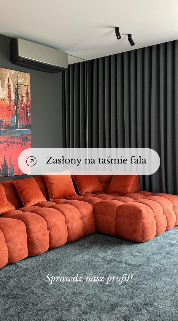 Ciemnoszare zasłony na taśmie fala, widoczne za narożnikiem z pomarańczowej tkaniny obiciowej i poduszkami w tym samym kolorze, na tle szarej ściany z abstrakcyjnym obrazem w odcieniach czerwieni...