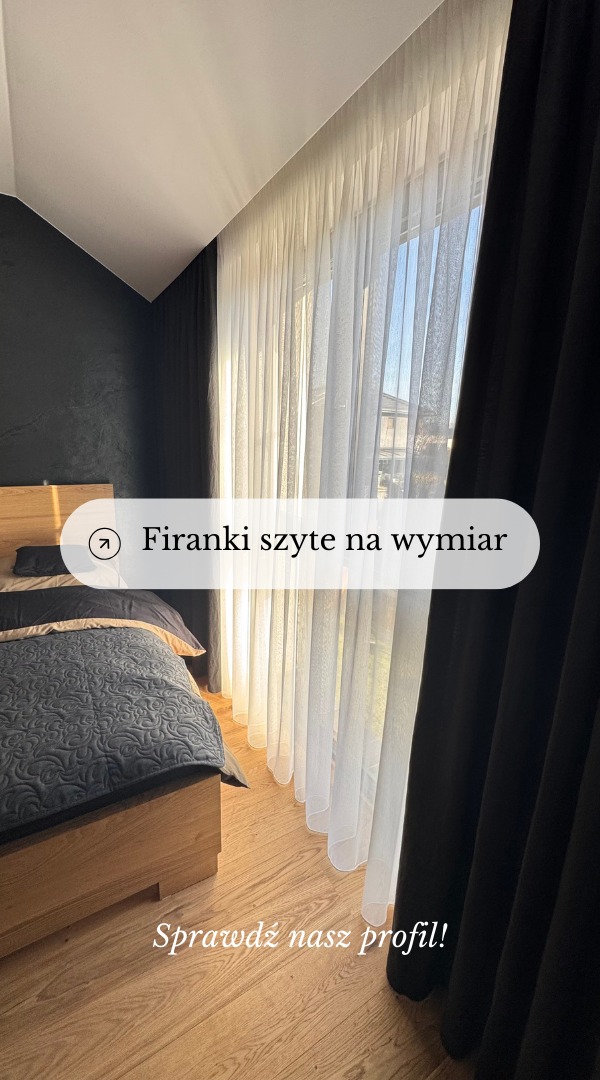 Sypialnia z czarną ścianą i jasnymi drewnianymi panelami podłogowymi, okno przesłonięte długimi, warstwowymi zasłonami: przejrzyste białe firany i ciężkie czarne zasłony po bokach.