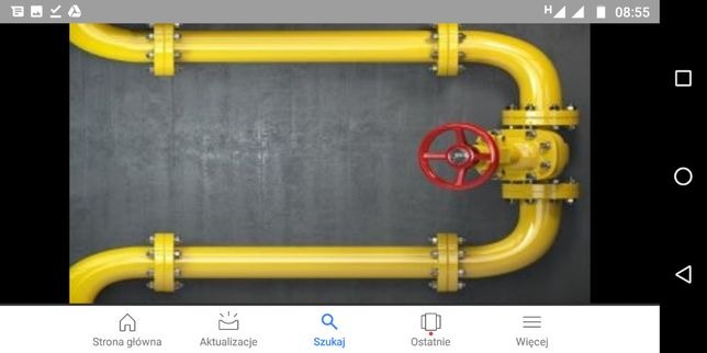 Żółta rura gazowa z czerwonym zaworem na tle szarej ściany, widok z przodu.