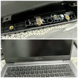 Uszkodzone mocowanie zawiasu matrycy w laptopie ASUS, widoczne ślady kleju i gwintowane tuleje mocujące; dolna część zdjęcia przedstawia klawiaturę laptopa.